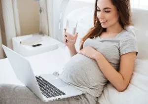 Pregnant woman drinking water while working according to alarm