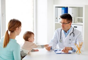 medicine, healthcare, pediatry and people concept - woman with baby and doctor at clinic