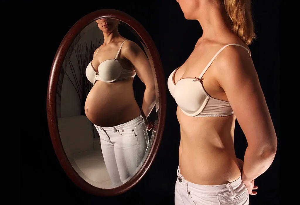 A woman looking into the mirror and imagining herself pregnant