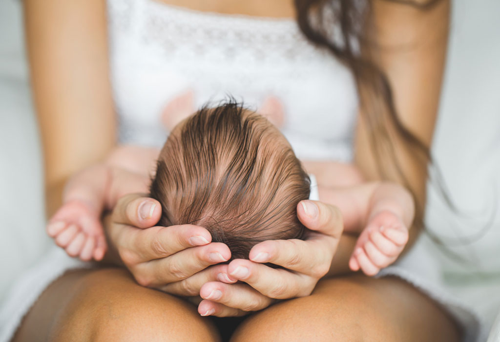 Mother supporting newborn's head and neck