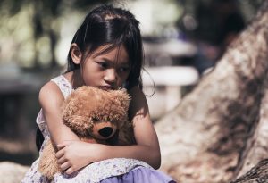 A little girl sitting with her teddy bear, feeling depressed