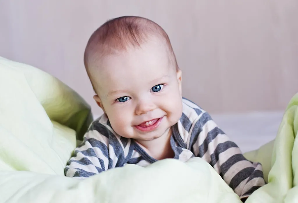 A baby laying on his stomach, smiling and showing its teeth