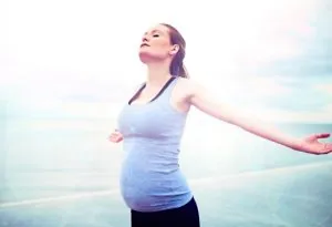 A pregnant woman exercising with her arms stretched out