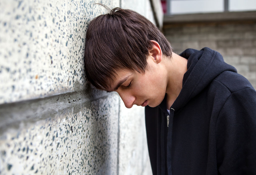 Teenage boy standing alone by a wall