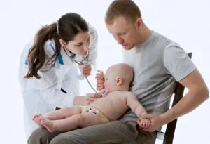 A doctor checking an infant sitting on the father's lap