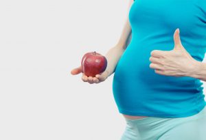 A pregnant woman holding an apple in her hand