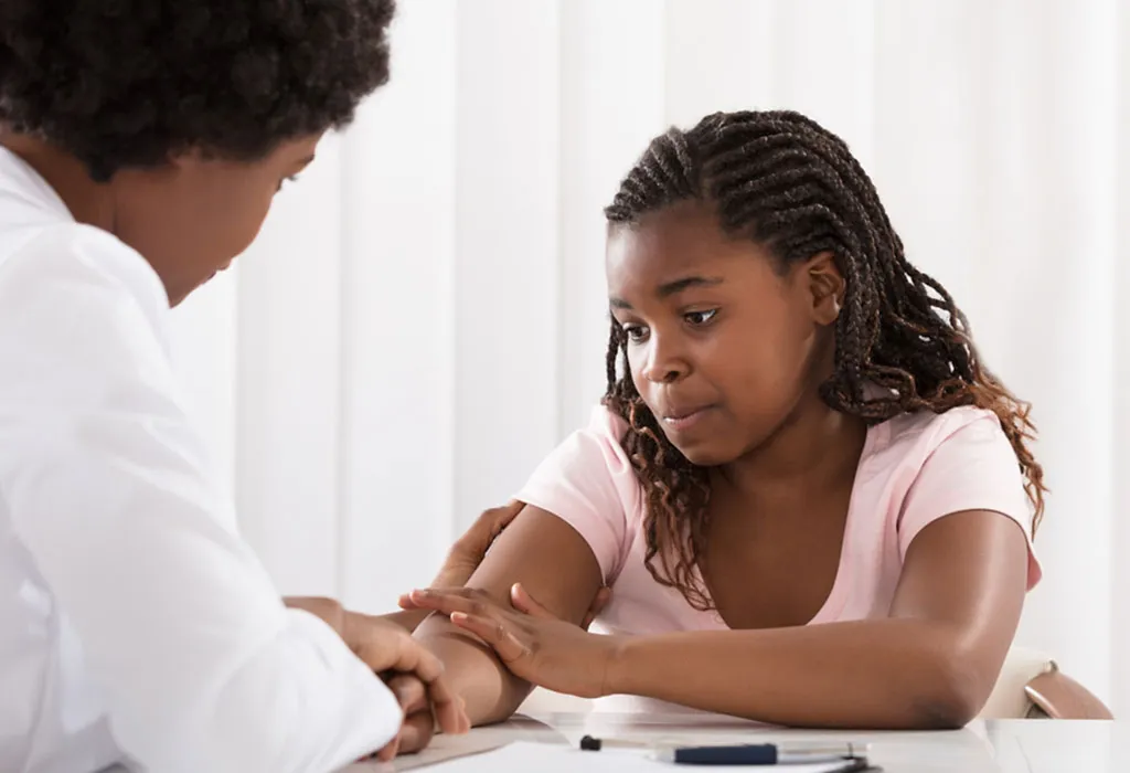 A female doctor comforting a teenage patient