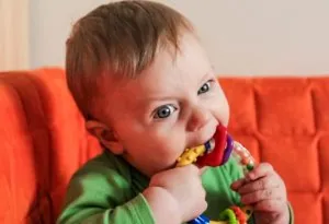 A 7-months-old baby gnawing a teether
