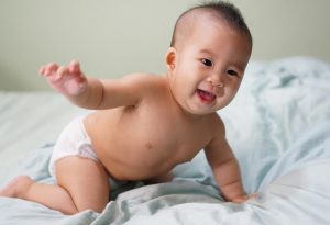 A six month-old baby crawling in bed
