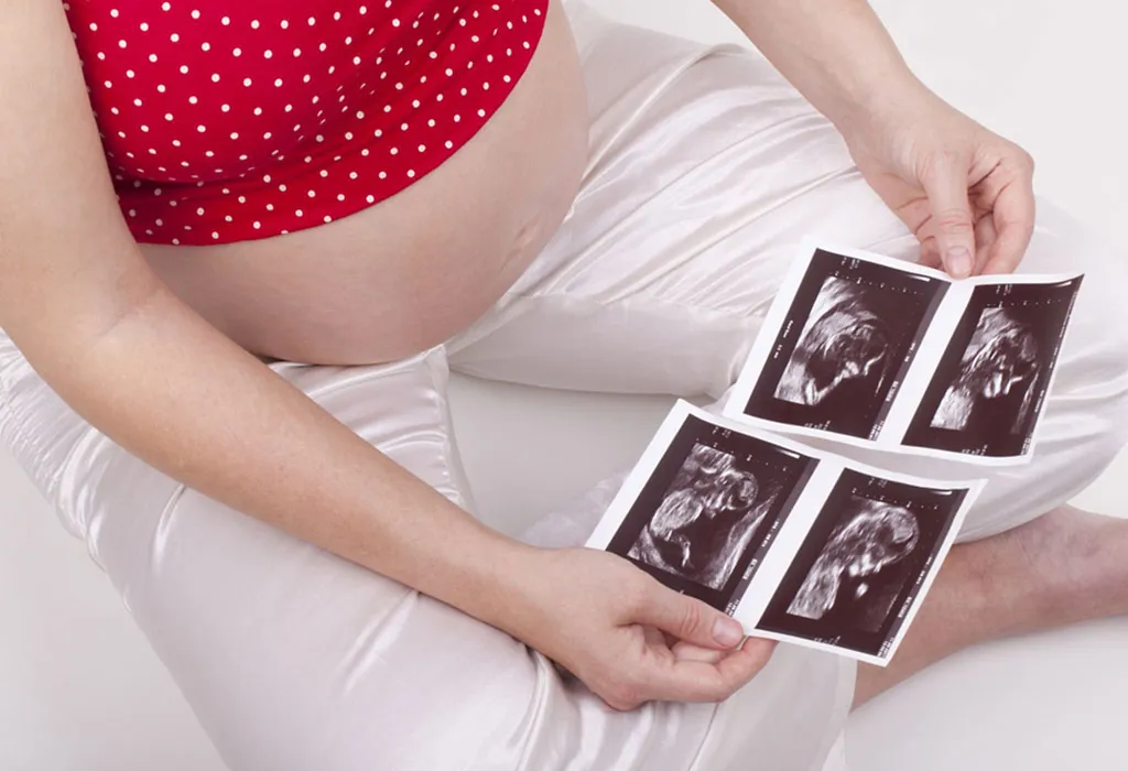 A pregnant woman looking at two ultrasound scans