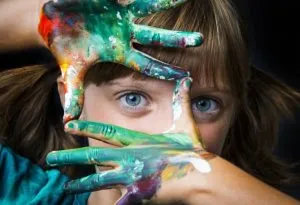 A little girl with her hands smeared in water colours