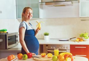 A pregnant woman eating a banana
