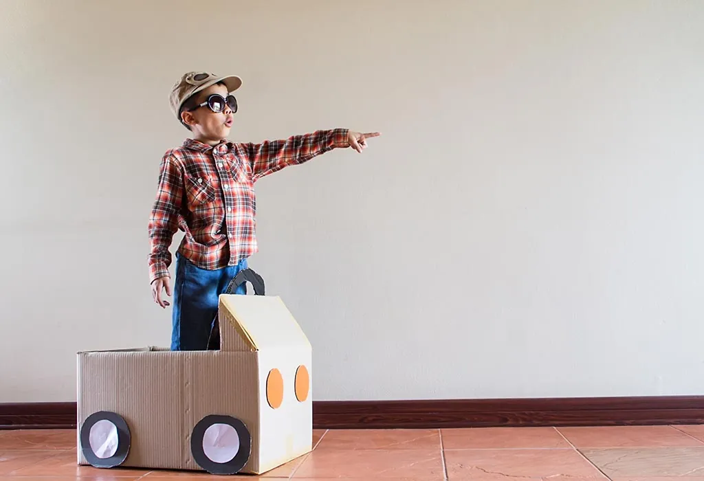 A little boy playing with a cardboard box car