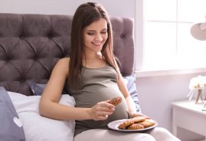A pregnant woman eating cookies