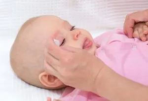 A mother cleaning her baby's eyes
