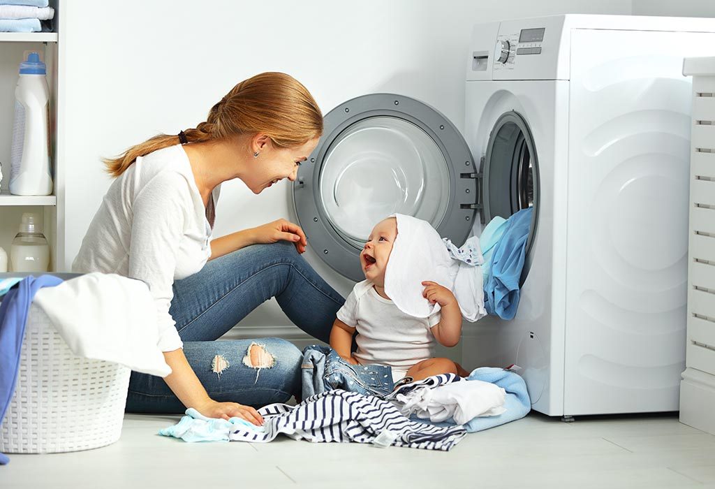 A mother washing clothes while playing with her baby