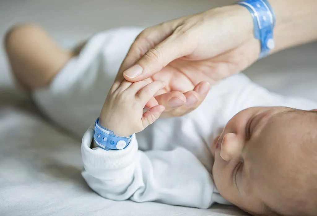 A mother holding her newborn son's hand