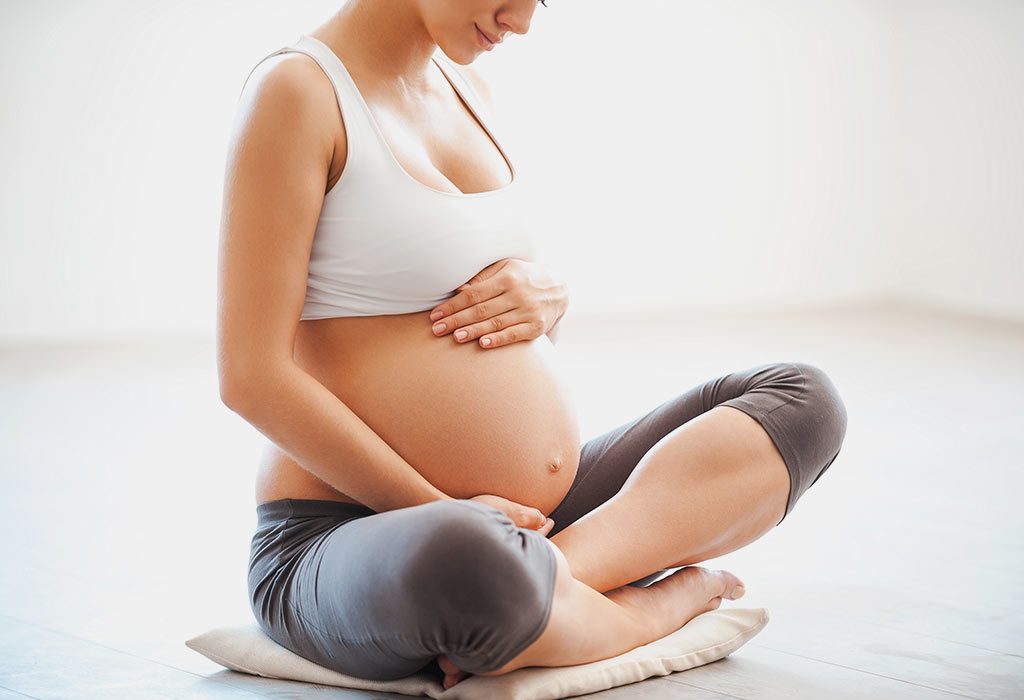  A pregnant woman holding her belly while sitting