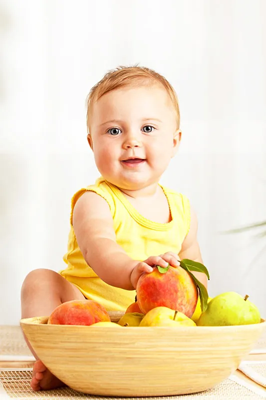 A baby holding a peach