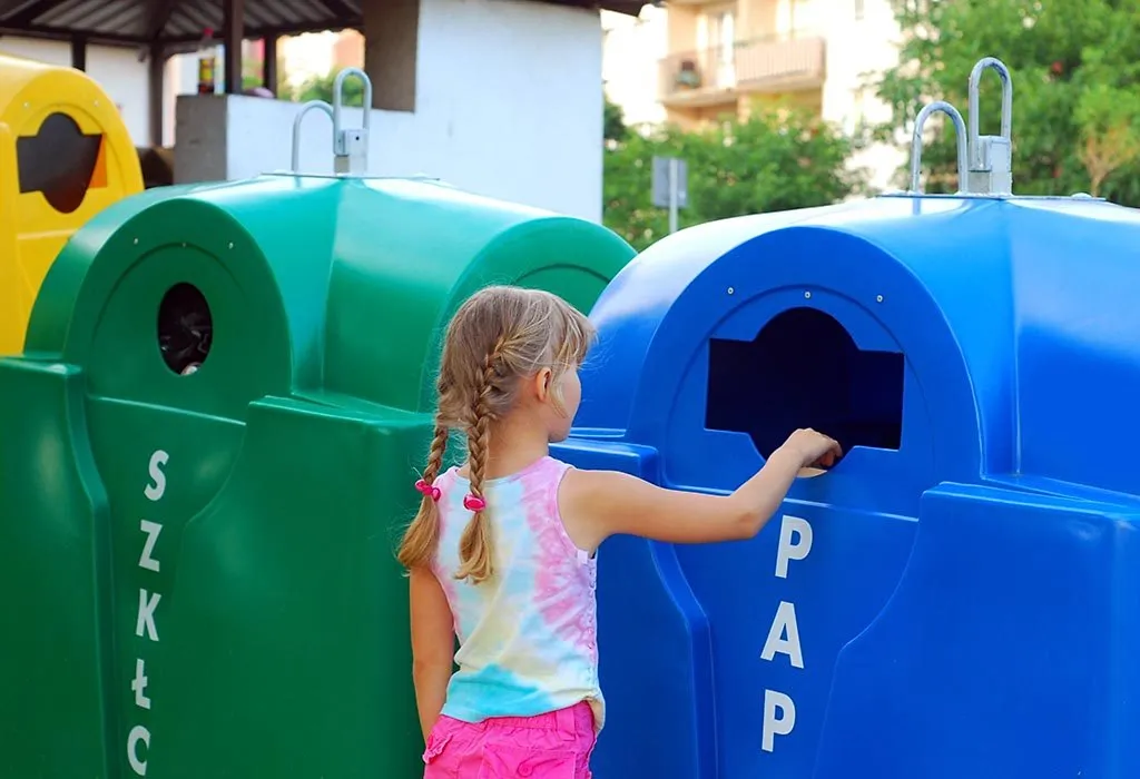A kid throwing paper in recycling trash bin