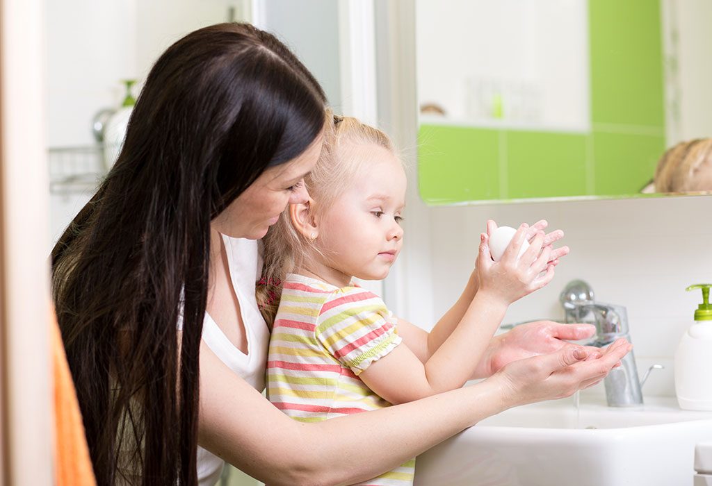 A mother teaches her daughter to wash hands