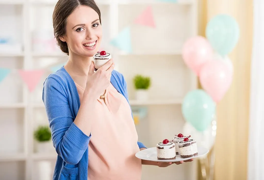 A pregnant woman eating a cake