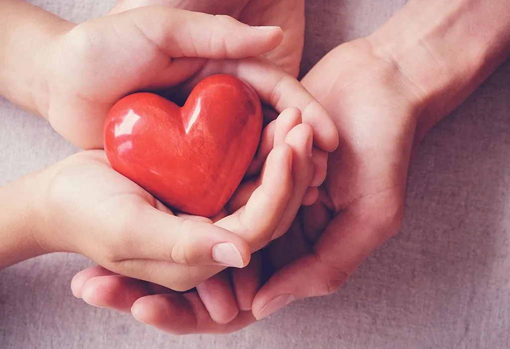 A child's hands holding a red heart.