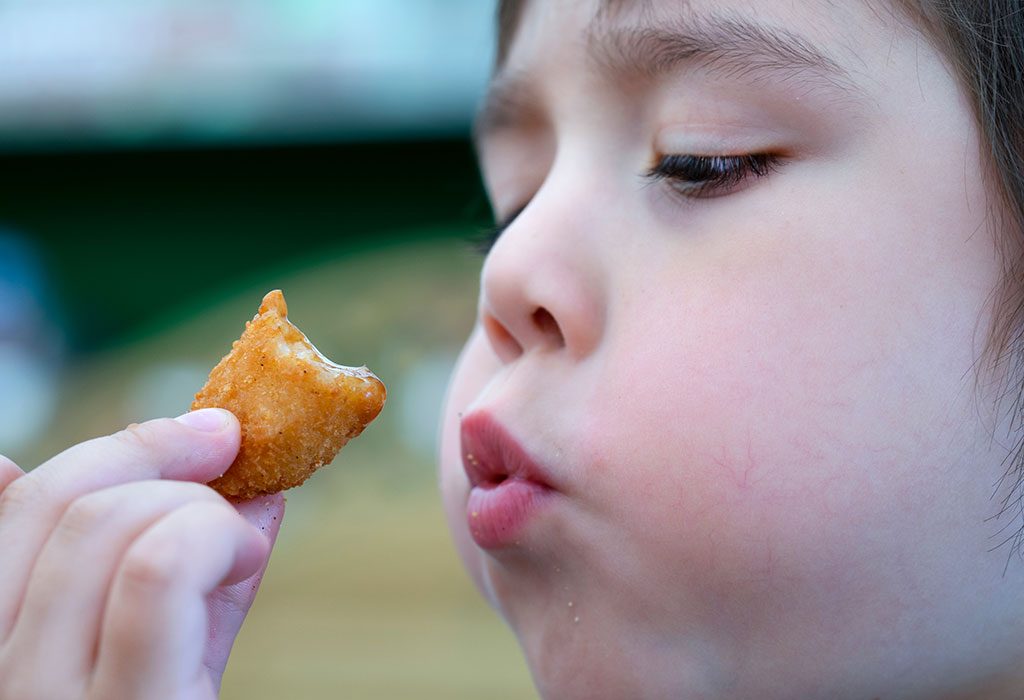 Toddler eating scampi, a kind of fish