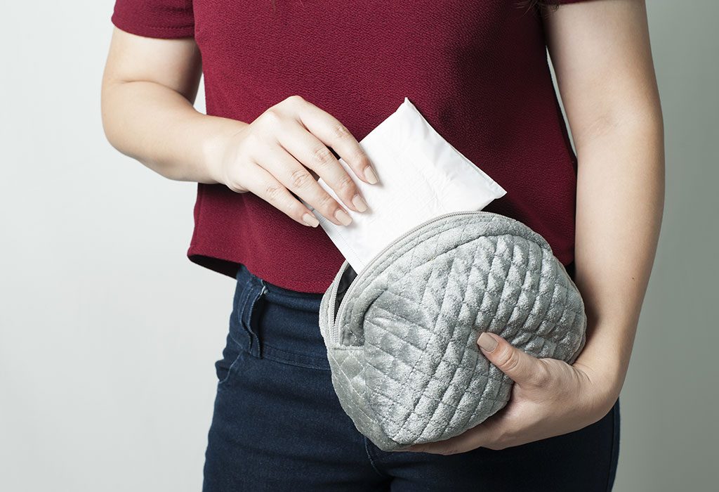 Woman putting maternity pad in bag