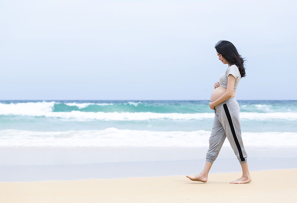 Pregnant woman walking on the beach