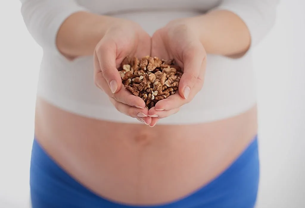 A pregnant woman with a handful of walnuts
