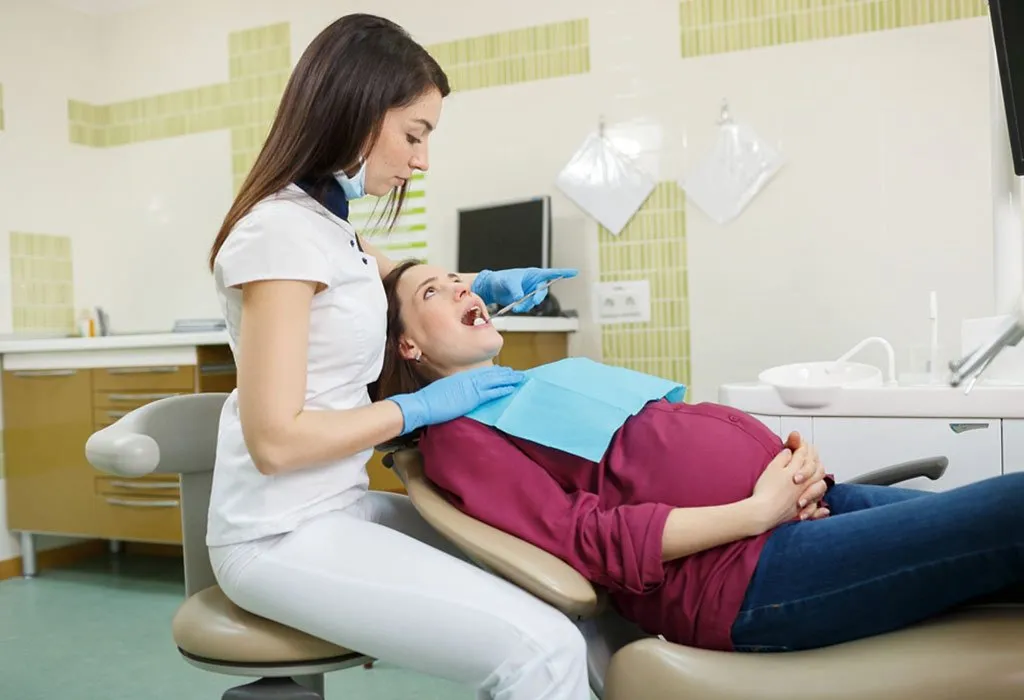 A dentist checks a pregnant woman's teeth