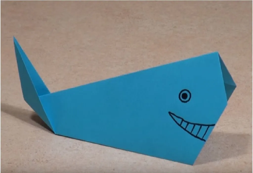 Using a marker and make the eyes and the mouth of the whale.