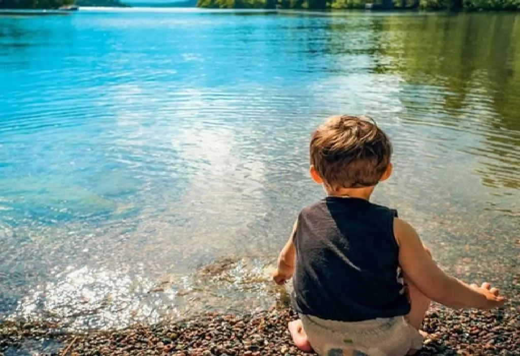 Child seating along lake side