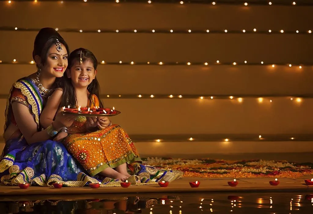 Mother and daughter light diyas in their home