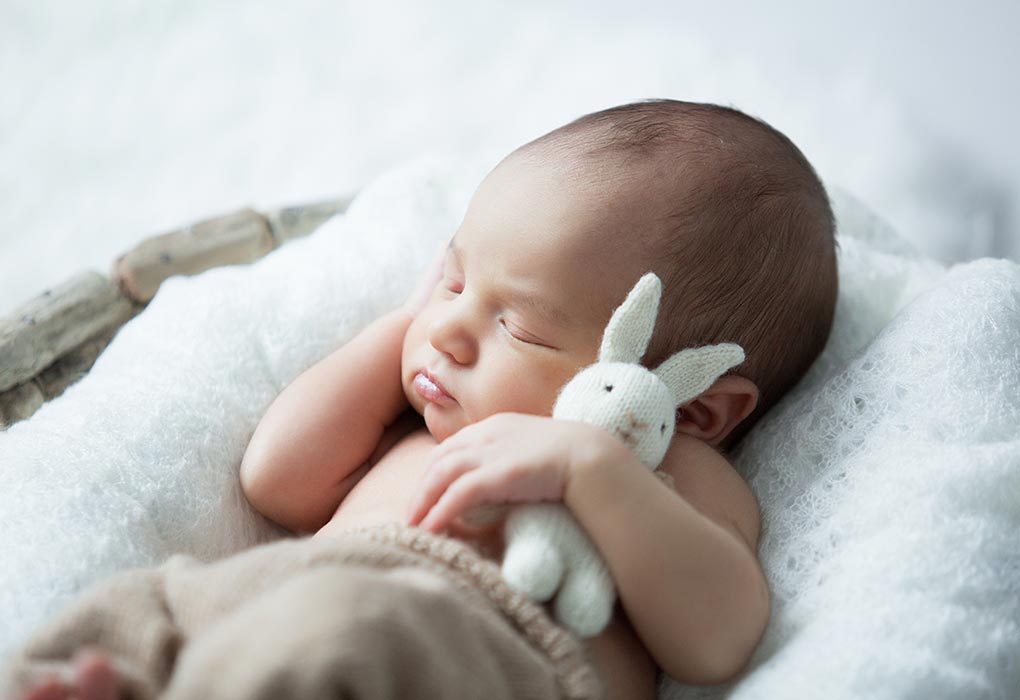 A baby sleeping with a toy