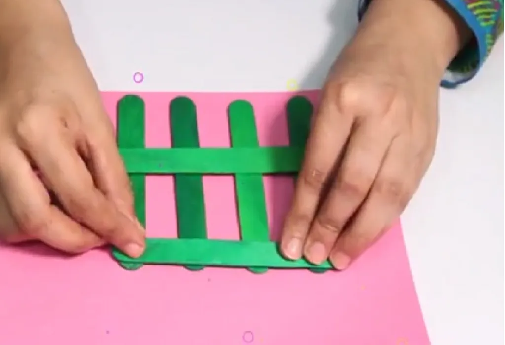 Place four popsicles sticks 2 inches apart. Place one popsicle stick across these four sticks towards the top and one large popsicle stick across the center to mark your photo frame. Stick them together using Fevicol/hot glue.