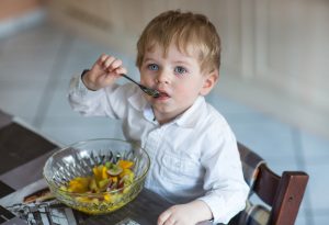 Een kind dat fruitsalade eet