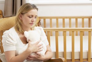 A woman sitting with a teddy, looking lonely and sad