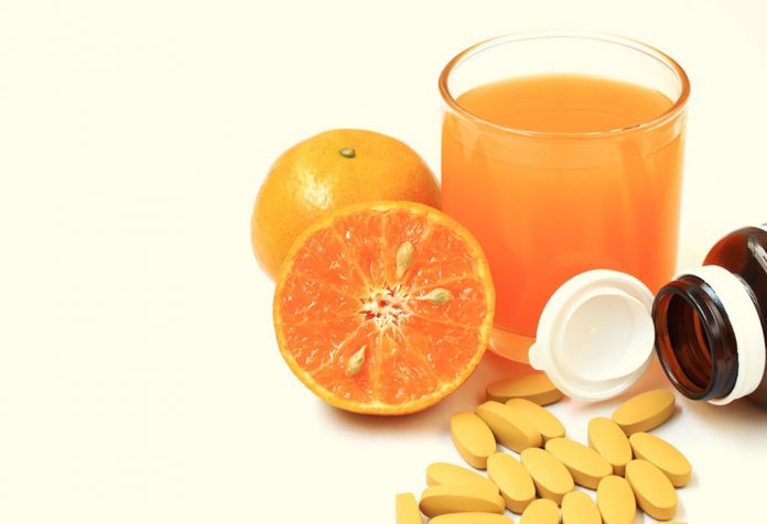 Vitamin C tablets and and an orange
