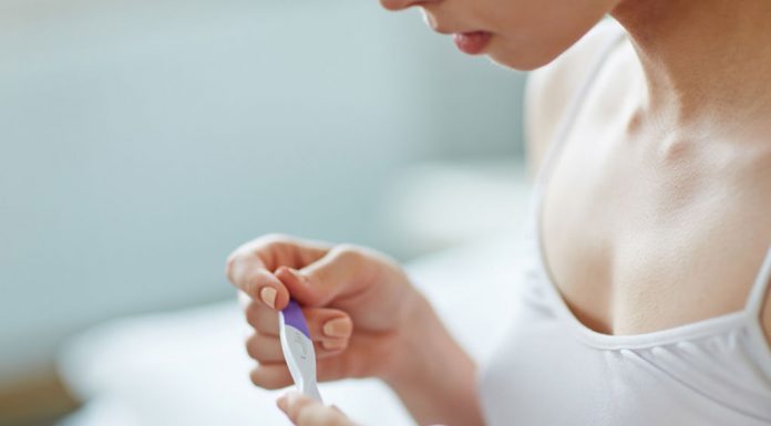 A young woman with a pregnancy test in her hand
