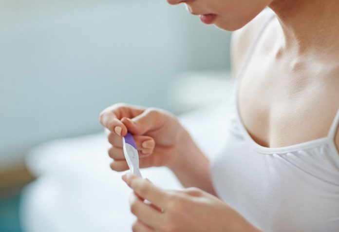 A young woman with a pregnancy test in her hand