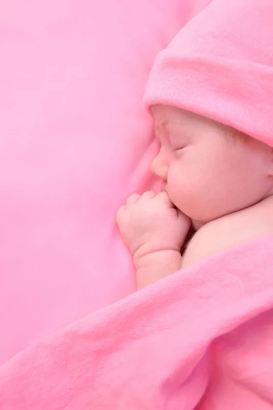 Newborn baby girl sleeping in a pink blanket