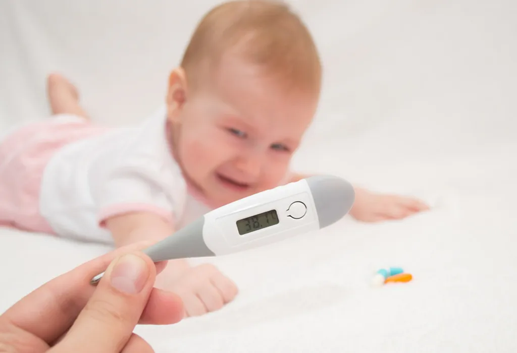 mother holds a thermometer and baby lying on bed