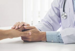 A doctor holding a patient's hand for encouragement