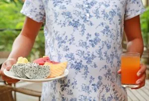 A pregnant woman holding a plate of fruits and a glass of juice