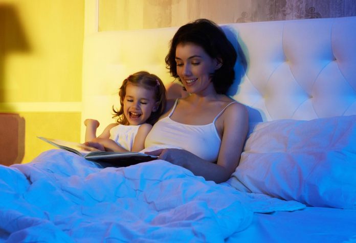 A mother and daughter reading a book together in bed