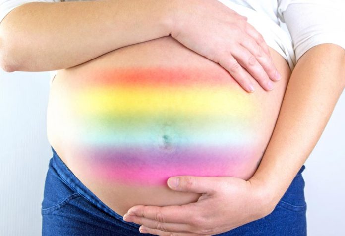 A pregnant woman with rainbow colours on her belly