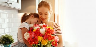 A little girl giving a bouquet of flowers to her mother