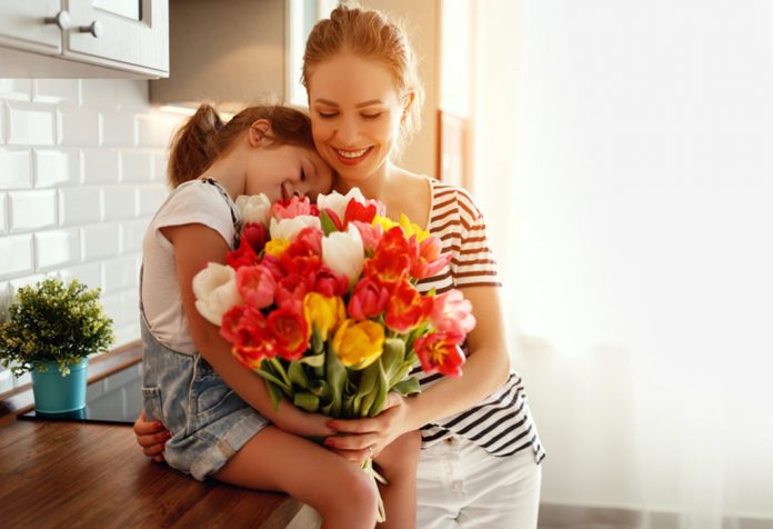 A little girl giving a bouquet of flowers to her mother